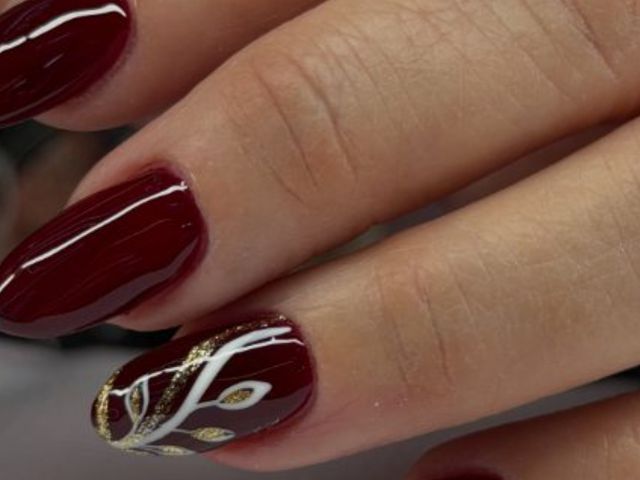 Uñas color vino con hojas doradas pintadas a mano en Más que Divas